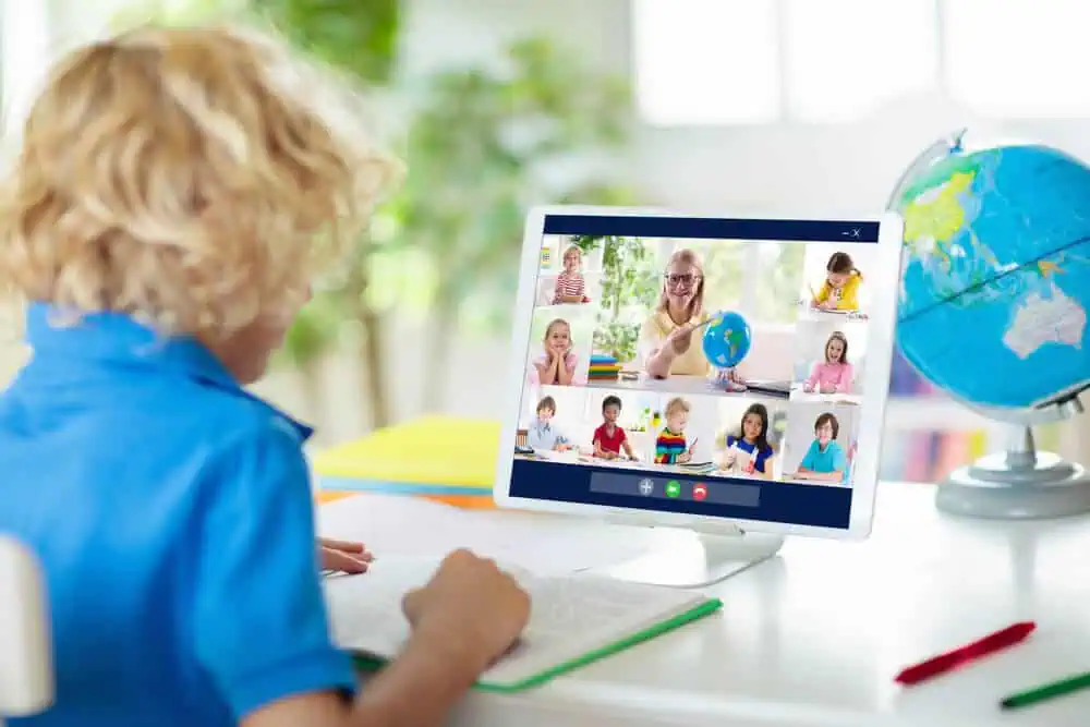 Child participating in a virtual classroom with a teacher via video call.