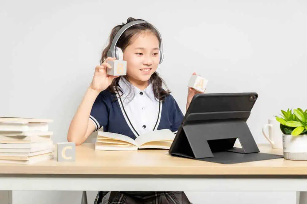 Young girl with headphones participating in online learning via tablet at home.