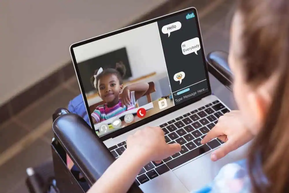 Child engaging in online learning via laptop with virtual classroom chat interface.