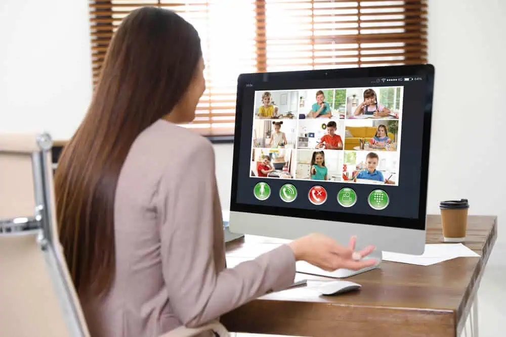 Woman participating in a virtual classroom with multiple students on screen.