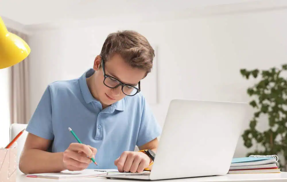 Student studying online with a laptop and notebook for remote learning.