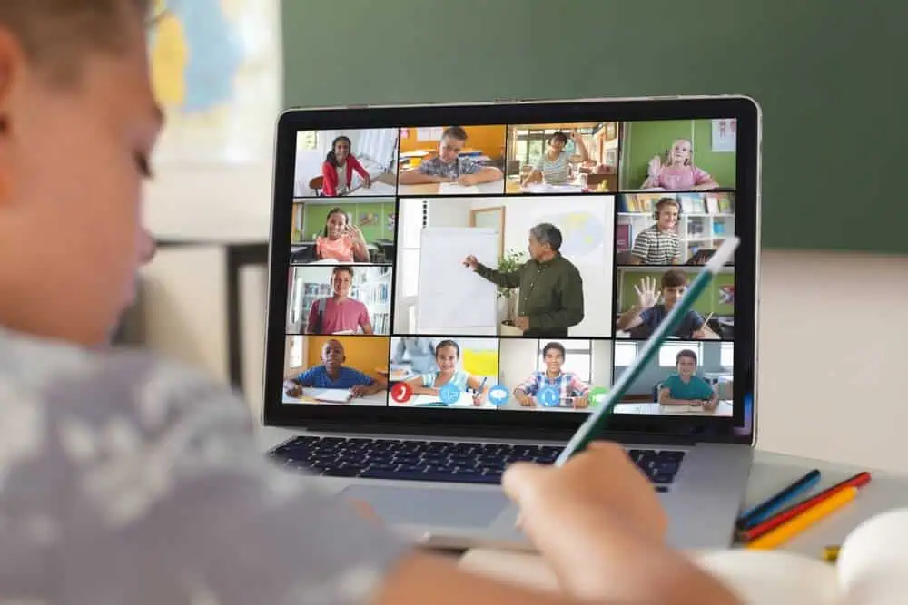 Virtual classroom with multiple students and teacher on a laptop screen.