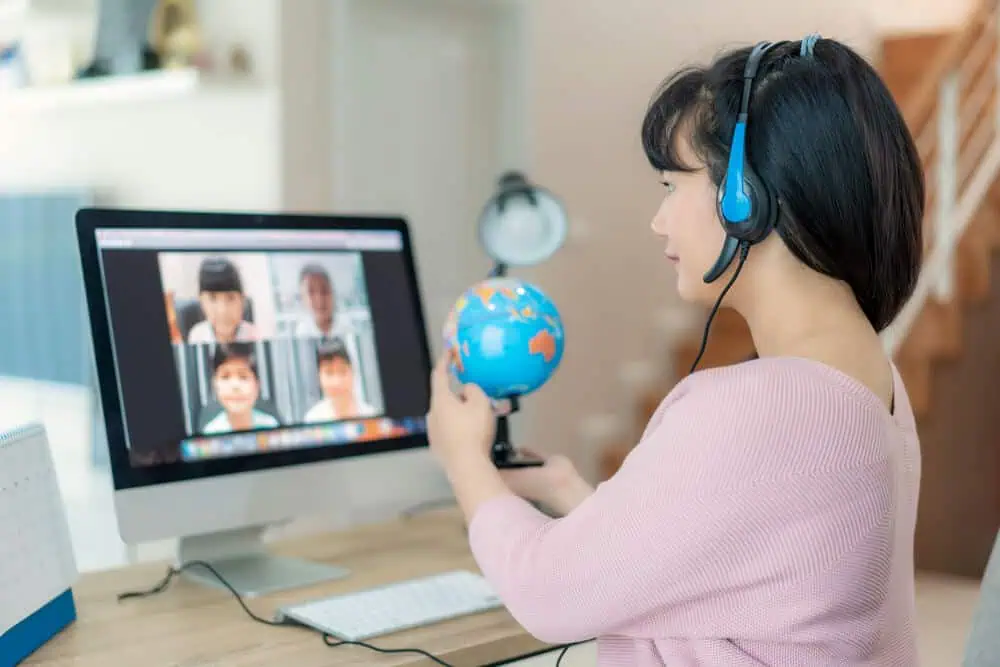 Student engaging in virtual classroom with headset and globe during online learning session.