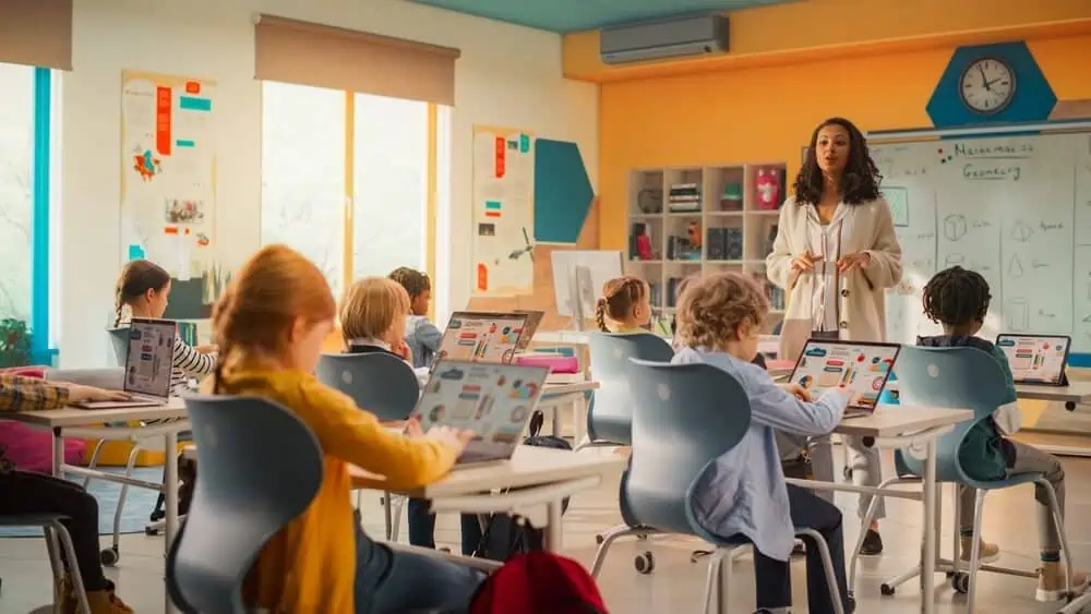 Engaged students in a modern classroom with a teacher using digital devices for remote learning.