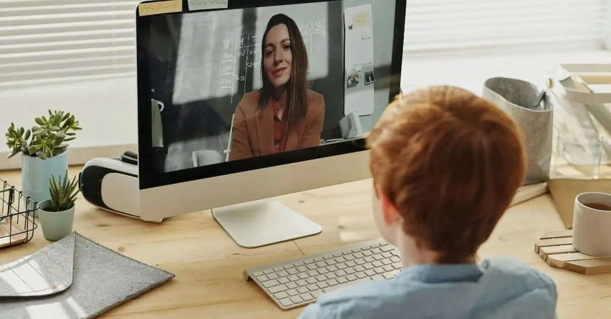 Student engaging in online learning with a teacher via computer.