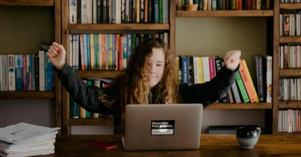Student engaging in remote learning with a laptop in a home library setting.