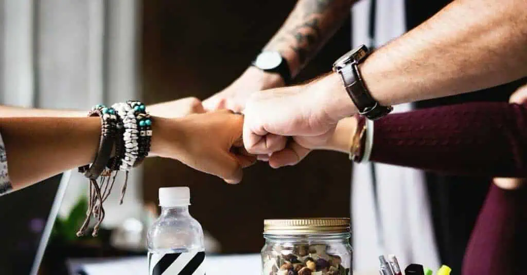 Diverse team members fist bump in a collaborative workspace, promoting teamwork and engagement.