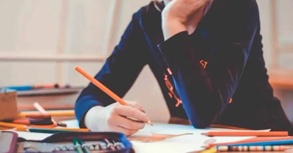 A k12 student expresses creativity by coloring with colored pencils.