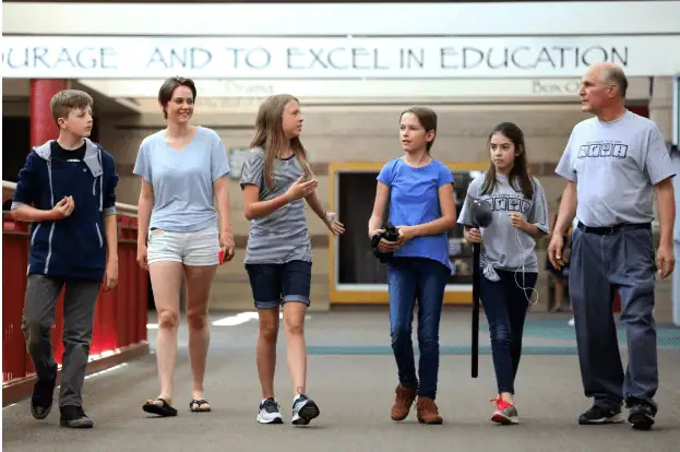 Group of students and teacher walking in school hallway for educational learning.
