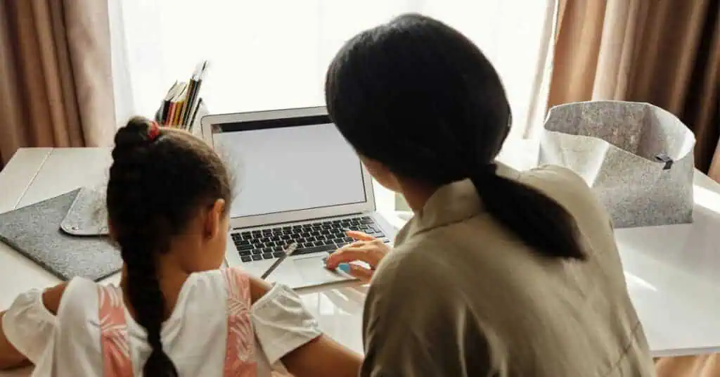 Woman and girl engaging in remote learning on a laptop at home.