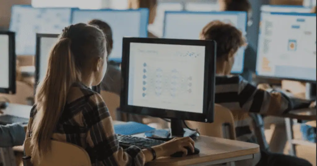 Students in a classroom using computers for remote learning and digital education.