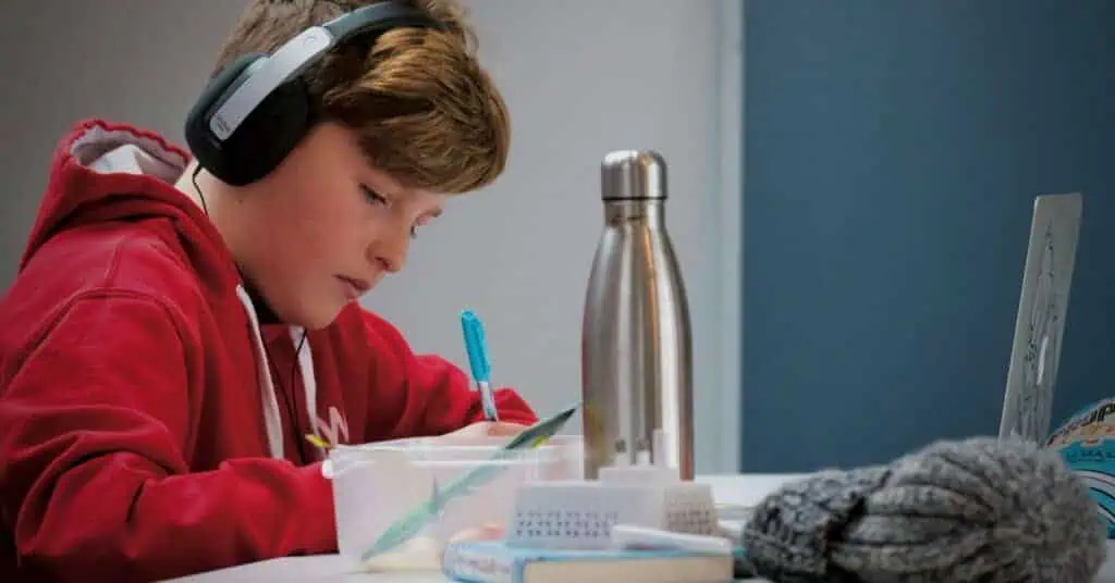 Student engaged in remote learning with headphones and laptop.