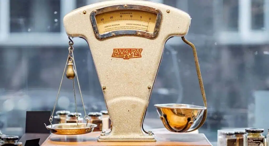Scale model of a vintage weighing scale with a brass bowl and weights.