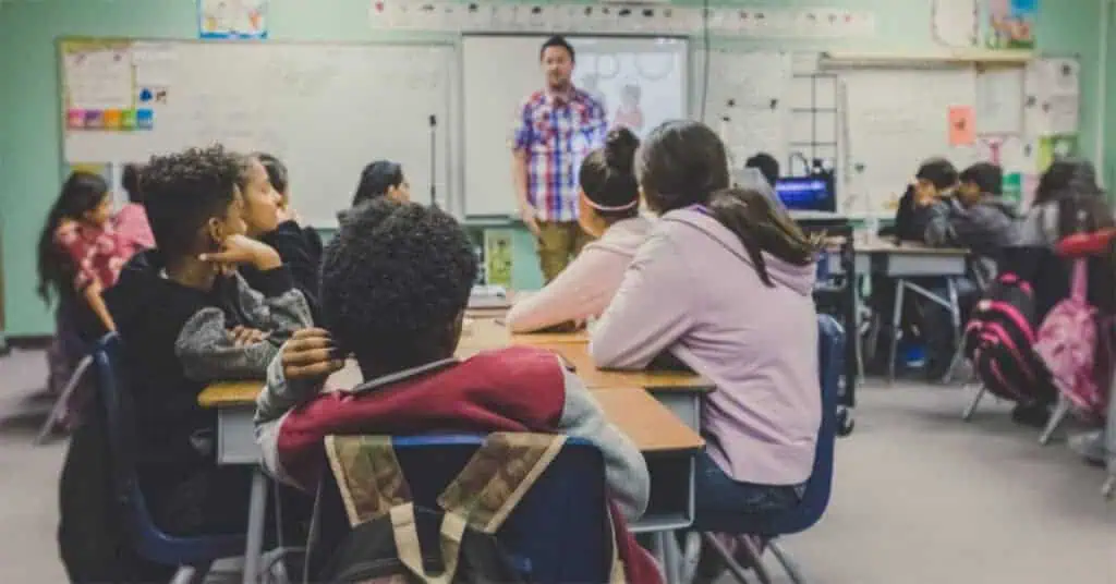 A diverse classroom of students listen to the teacher.