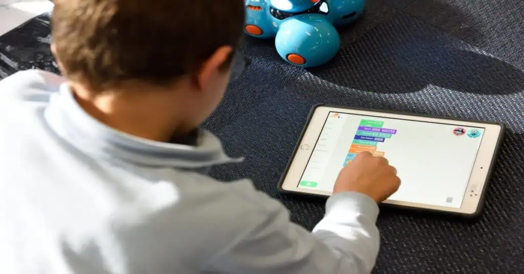 Student engaging with coding on a tablet for remote learning.