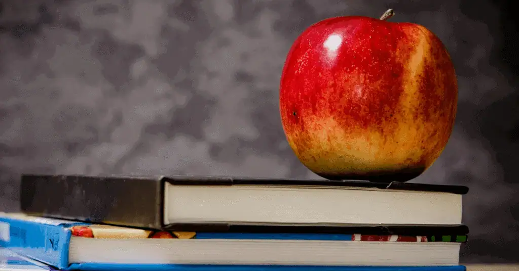 Apple resting on stacked books, symbolizing education and learning.