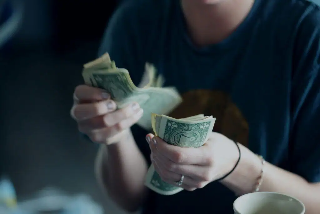 Student counting cash, representing financial aid or funding in online education.