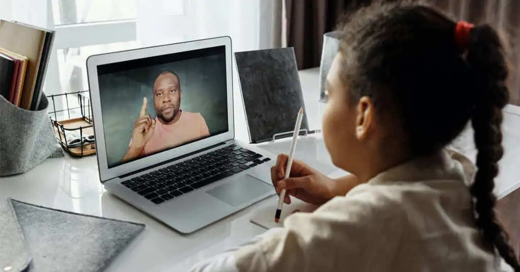 A student watches intently as their virtual teacher leads a lesson solving educational equity.
