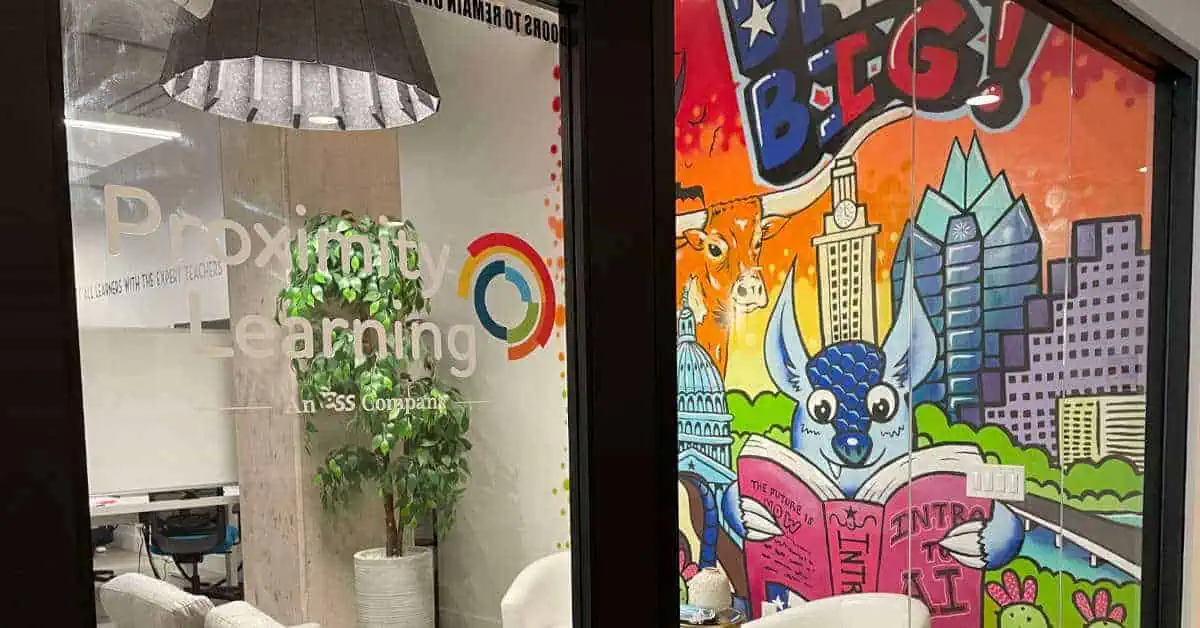 Proximity Learning logo on office glass wall with plant in background.