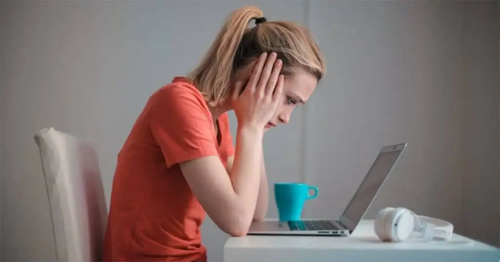 Student frustrated during online learning session with laptop at home.