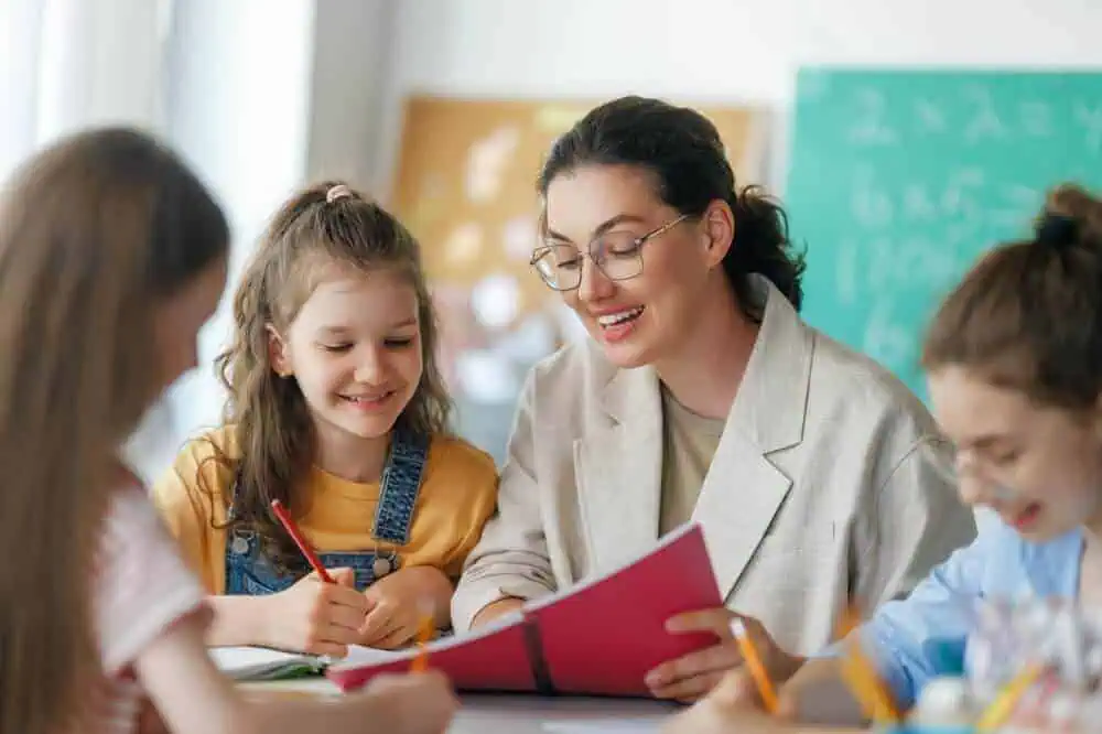 Teacher engaging with young students in a classroom setting for remote learning.