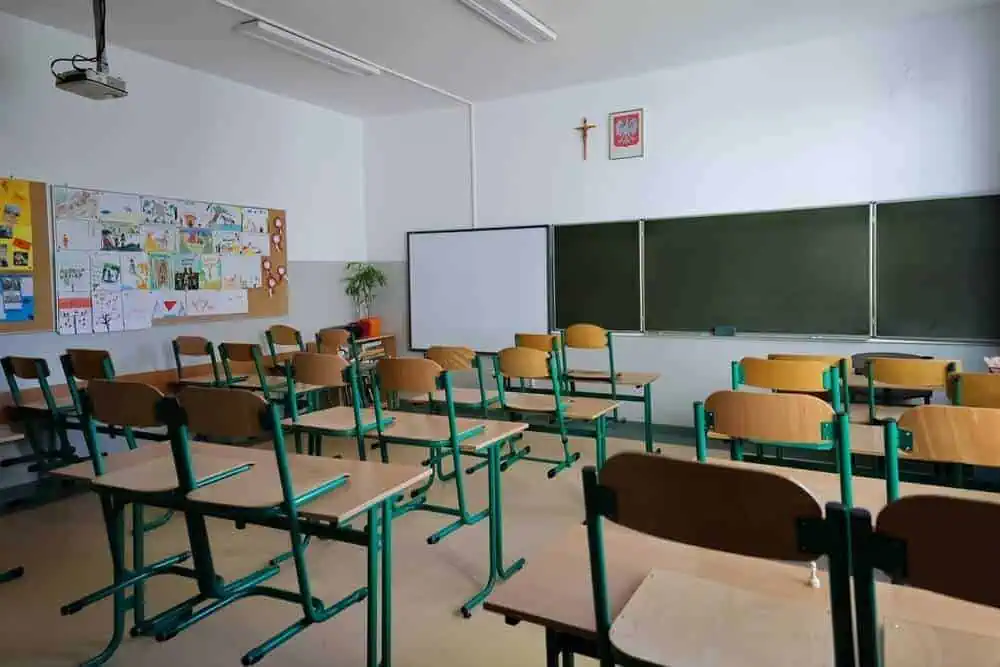 Empty classroom with desks, chairs, blackboard, and educational posters.
