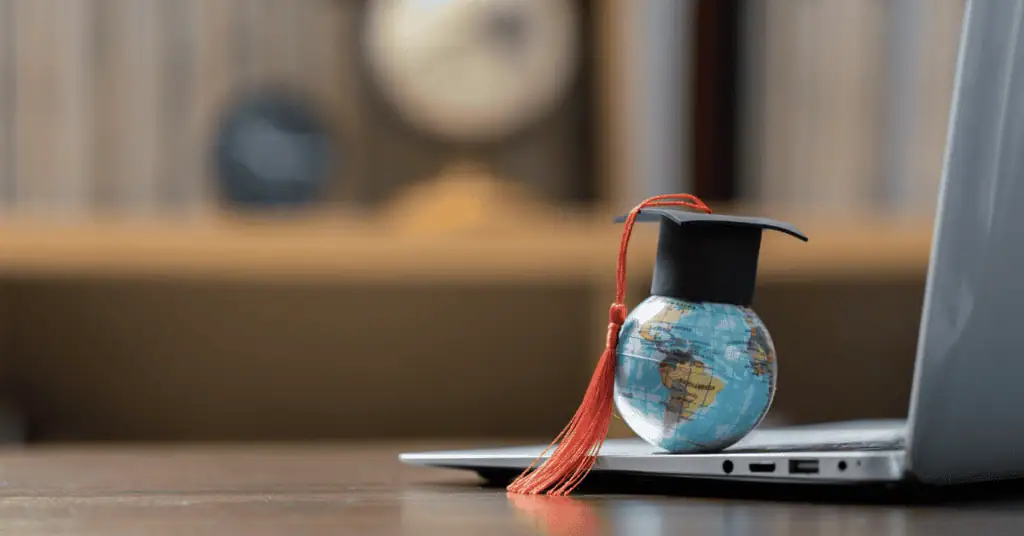 Graduation cap with globe on laptop, symbolizing online education and remote learning.