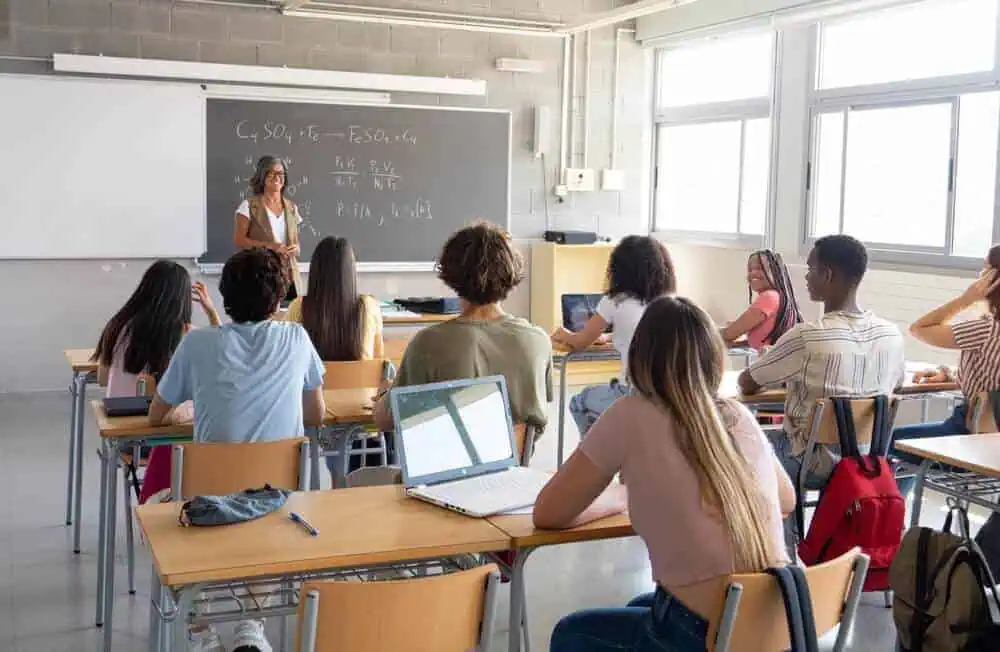 A female teacher educating middle school students in class in front of a blackboard