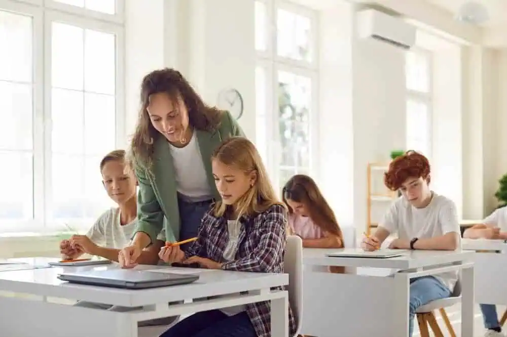 A female teacher helping a young female student with classwork