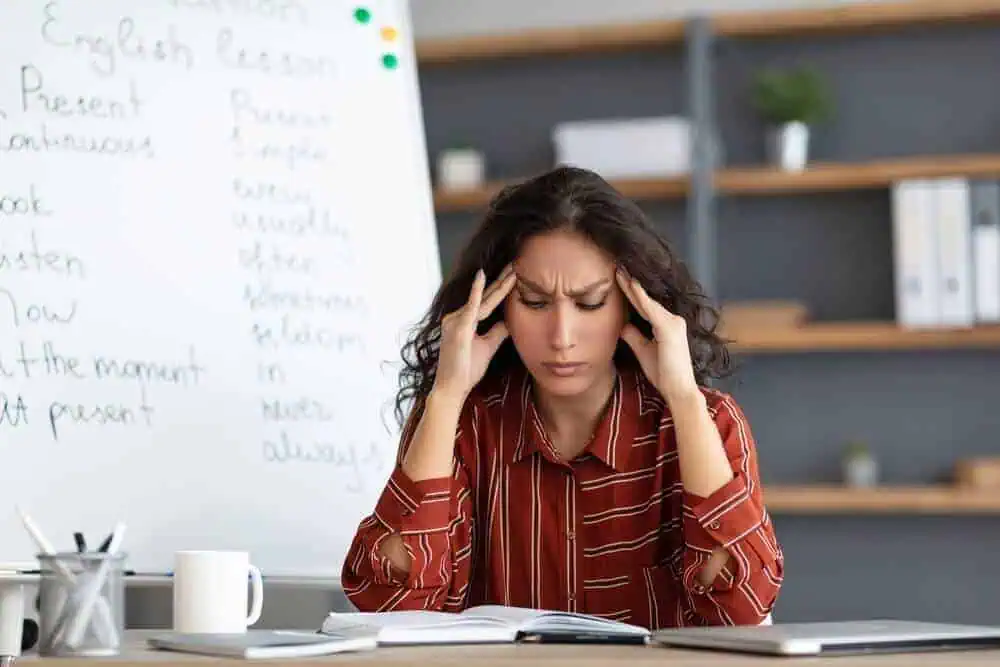 A female English teacher rubbing her temples from frustration