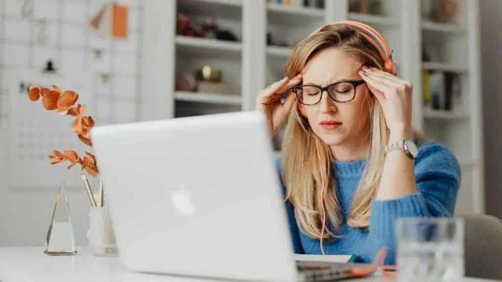 A teacher wearing headphones feels burnt out and stress in their zoom classroom.