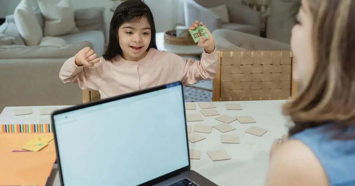 Young girl engaging in online learning with a teacher via laptop.