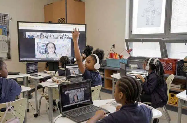 Students engaging in remote learning with headphones in a classroom setting.