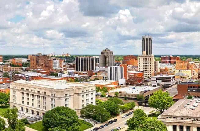 Aerial view of a city skyline with tall buildings and green trees, showcasing urban education hubs.