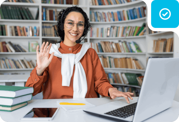 Woman teacher in library with laptop, promoting online learning and virtual classrooms.