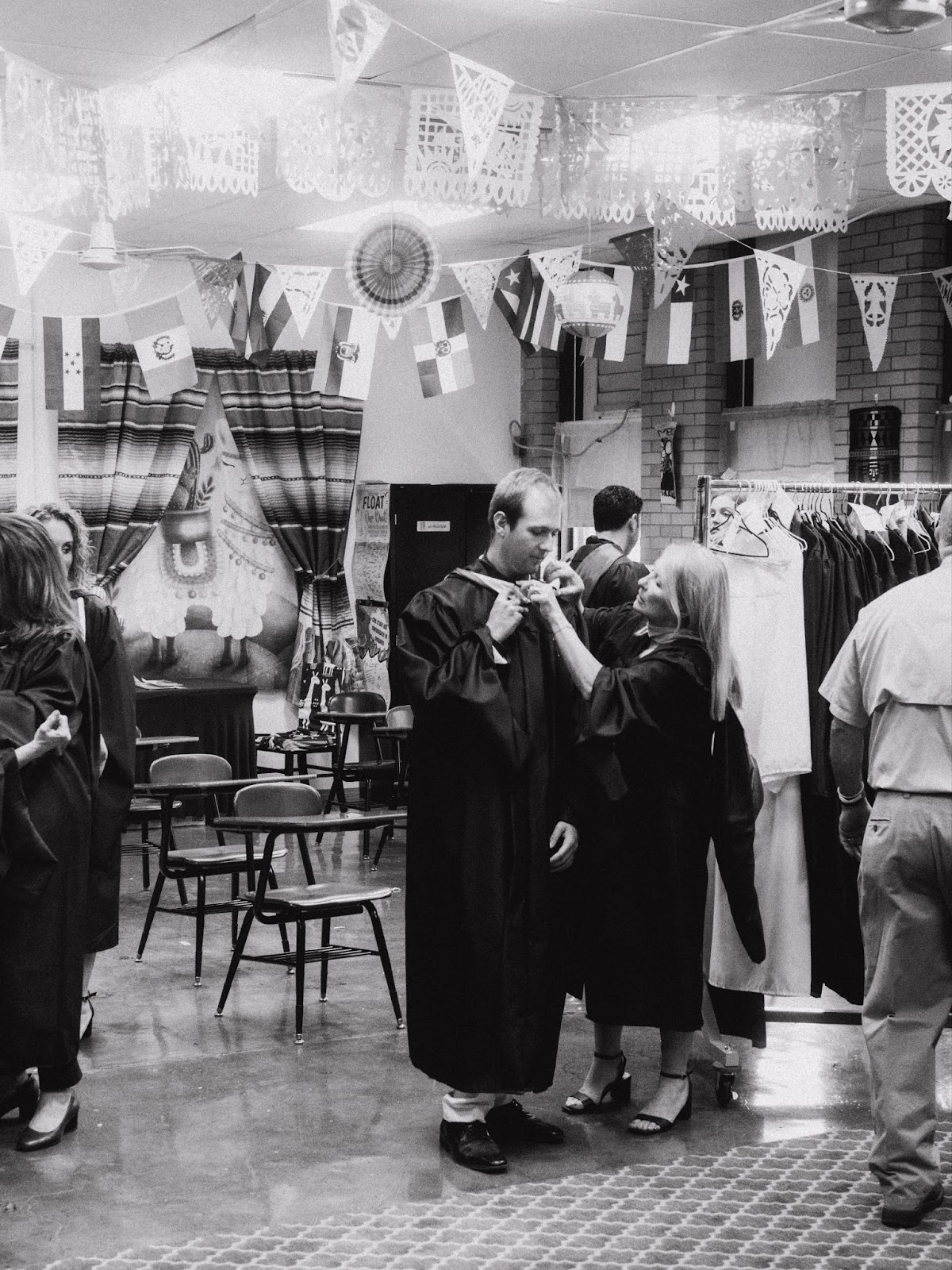 female teacher adjusts regalia stoll on male teacher
