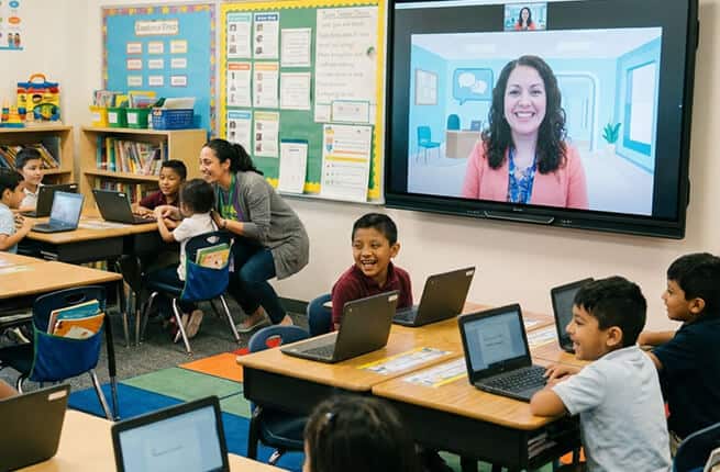 Students engaging in remote learning with a teacher via video conference in classroom.