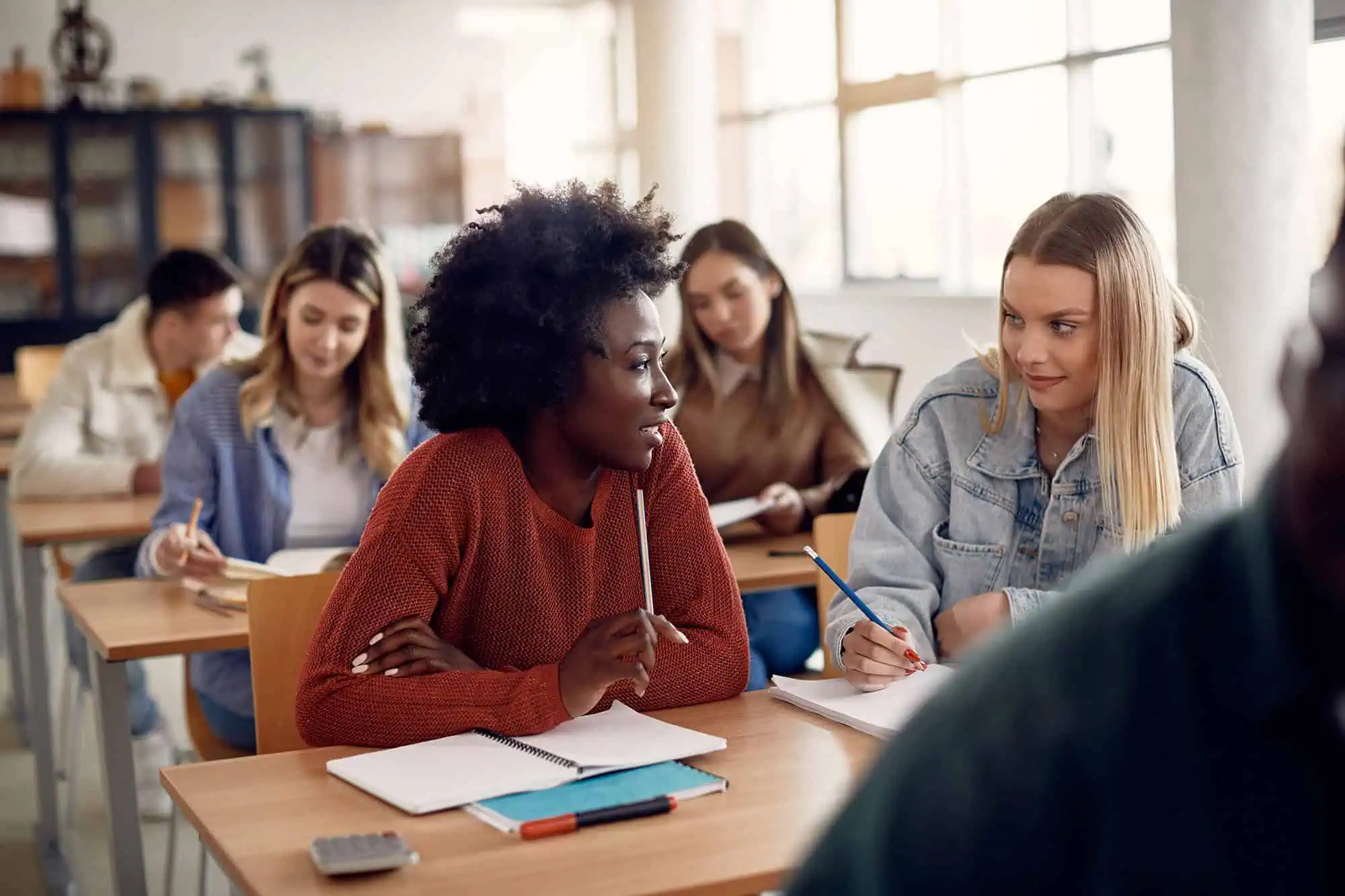 Diverse students participating in a classroom discussion with a teacher.